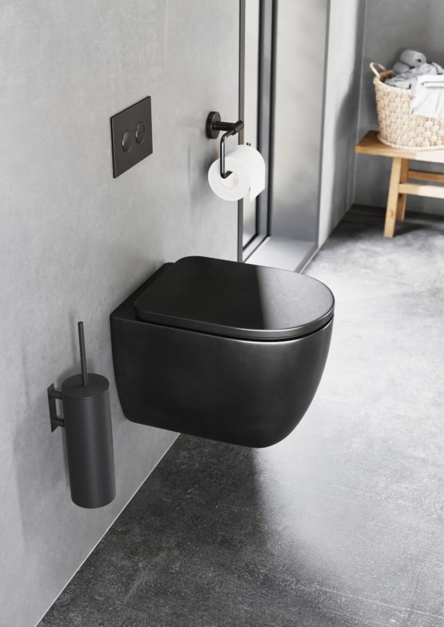 Badeværelse med sort toiletbørste, toilet, skylleknap og toiletrulleholder